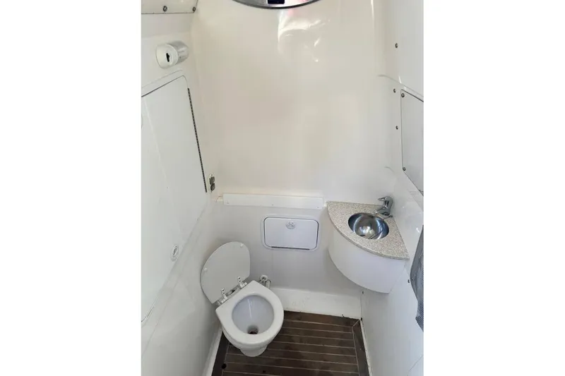 Slide: The Image of 2015 Regulator 28 Forward Seating boat bathroom with toilet and sink. - 28