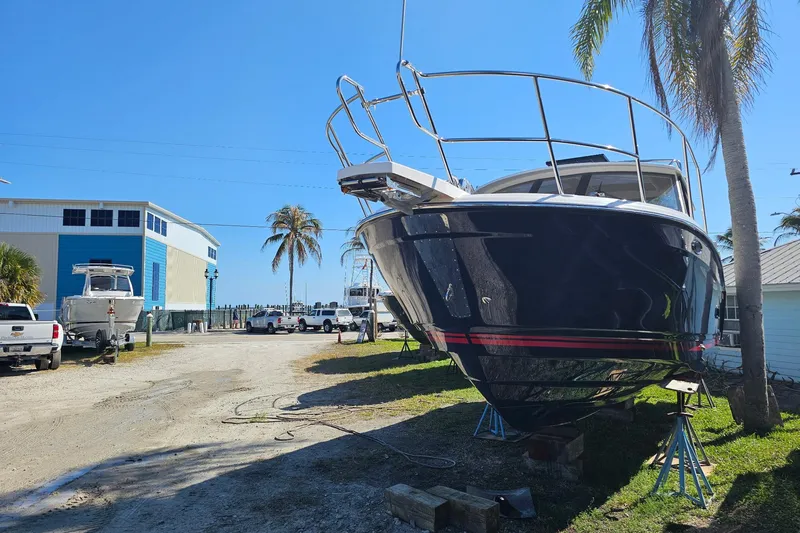 Slide: The Image of 2026 Cutwater C-288 Coupe boat on stands, sunny marina setting with palm trees. - 3