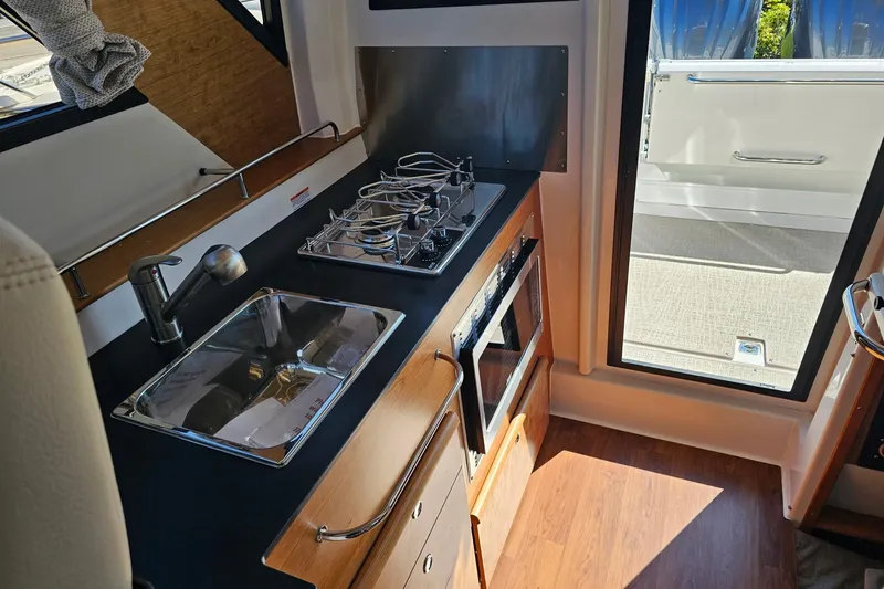 Slide: The Image of 2026 Cutwater C-288 Coupe interior kitchen with sink, stove, and oven. - 6