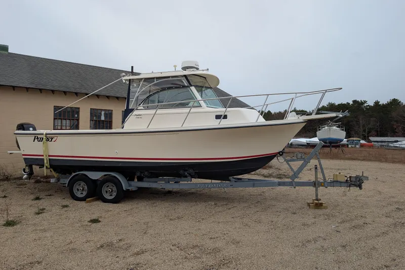 Slide: The Image of 2008 Parker 2510 XL Walkaround boat on trailer, parked outdoors near a building. - 2
