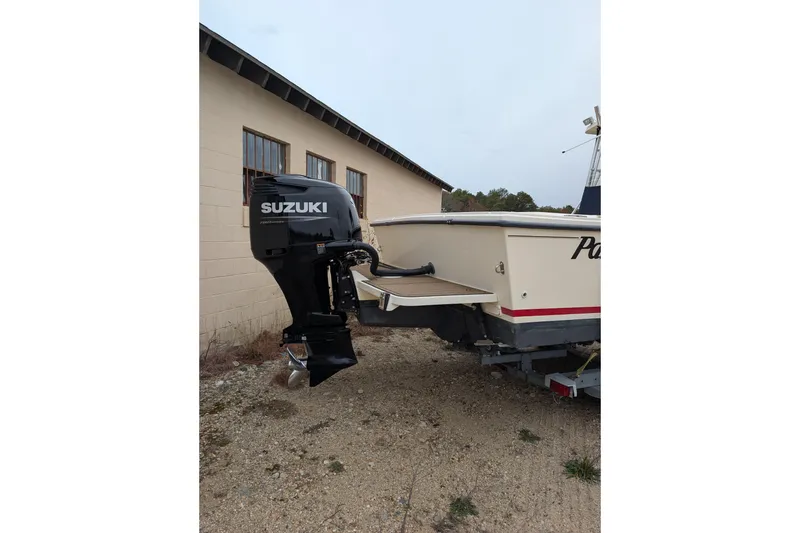 Slide: The Image of 2008 Parker 2510 XL Walkaround boat with Suzuki outboard motor, parked near a building. - 3