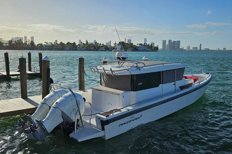 Slide: The Image of 2020 Axopar 37 XC Cross Cabin boat docked with city skyline in background. - 2