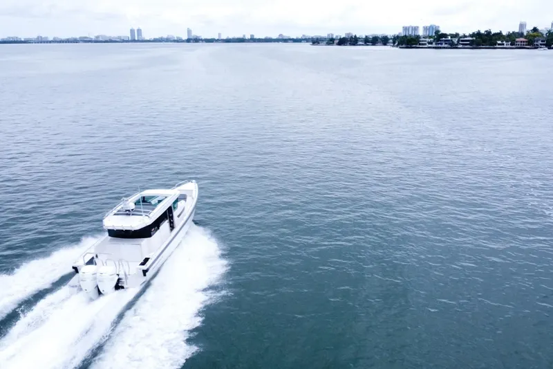 Slide: The Image of 2020 Axopar 37 XC Cross Cabin cruising on open water, city skyline in background. - 21