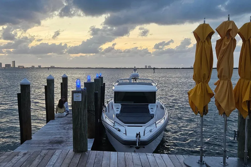 Slide: The Image of 2020 Axopar 37 XC Cross Cabin docked at sunset with yellow umbrellas nearby. - 9