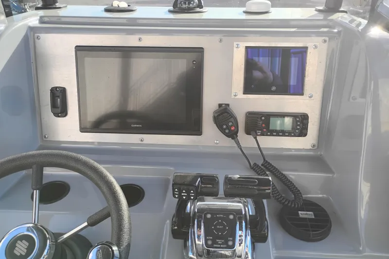 Slide: The Image of Control panel of a 2008 Valiant PT-750 boat with steering wheel and navigation equipment. - 12