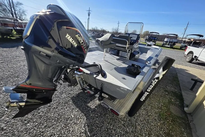 Slide: The Image of 2026 Xpress H24B Bay boat with Yamaha engine, parked on gravel lot. - 11