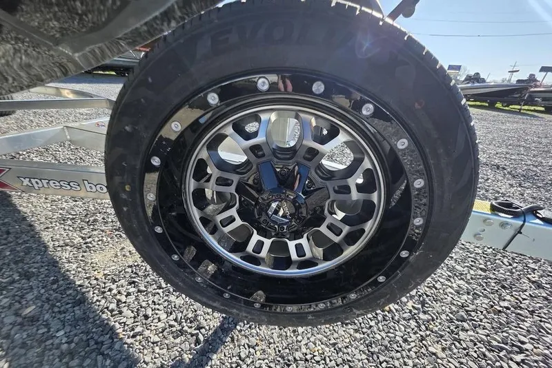 Slide: The Image of Close-up of a 2026 Xpress H24B Bay wheel on gravel, showcasing intricate rim design. - 14