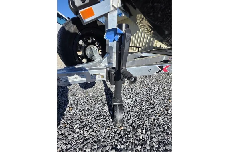 Slide: The Image of Trailer hitch of 2026 Xpress H24B Bay boat on gravel surface. - 15