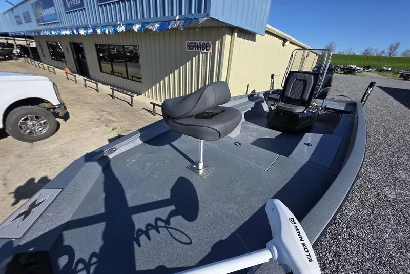 Slide: The Image of 2026 Xpress H24B Bay boat with seating, parked outside a service building. - 18