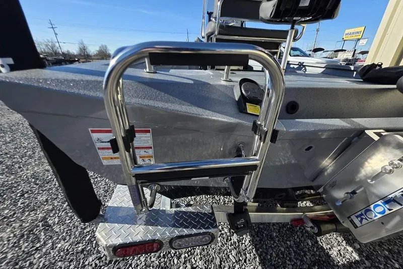 Slide: The Image of 2026 Xpress H24B Bay boat with ladder and motor, parked on gravel. - 6