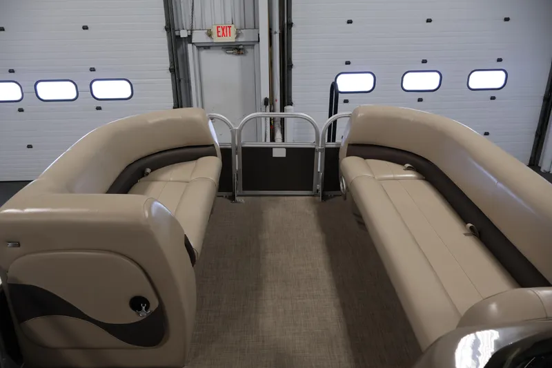 Slide: The Image of 2023 Sun Tracker Party Barge 18 DLX interior with beige seating in a garage setting. - 11