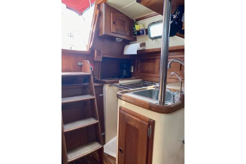 Slide: The Image of Interior of 1995 Pacific Seacraft Crealock 34 sailboat, featuring wooden cabinetry and compact kitchen. - 16