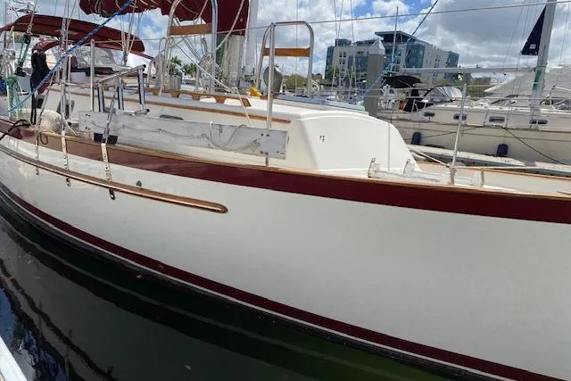 Slide: The Image of 1995 Pacific Seacraft Crealock 34 sailboat docked in marina, featuring red and white hull. - 38