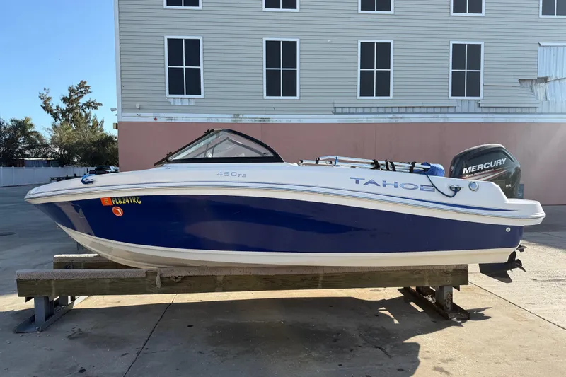 Slide: The Image of 2016 Tahoe 450 TS boat with Mercury engine, parked outdoors on a wooden stand. - 0