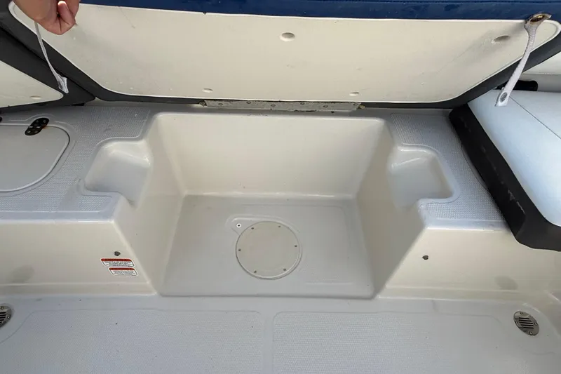 Slide: The Image of 2016 Tahoe 450 TS boat storage compartment with open lid and seating area. - 11