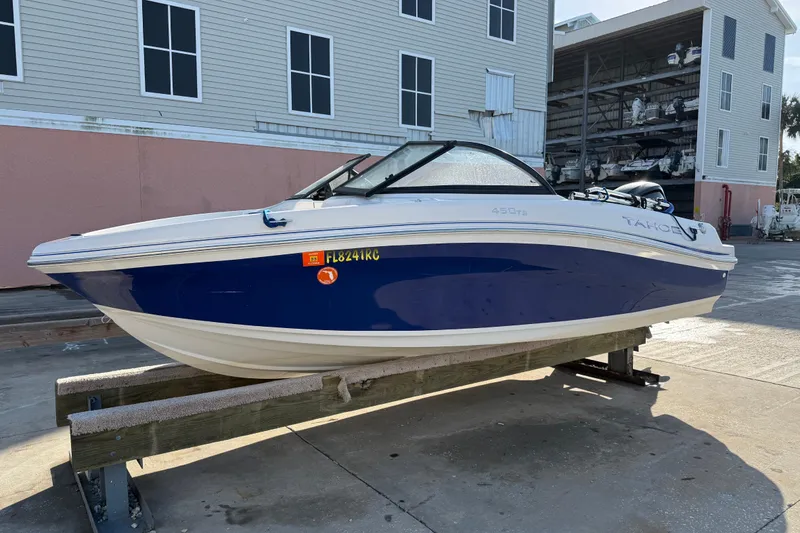 Slide: The Image of 2016 Tahoe 450 TS boat in dry dock, blue and white hull, marina background. - 2