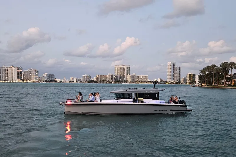 Slide: The Image of 2021 Axopar 37 XC Cross Cabin cruising near city skyline at sunset. - 2