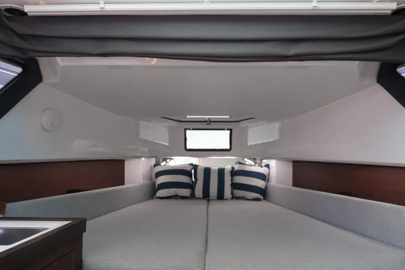Slide: The Image of 2021 Axopar 37 XC Cross Cabin interior with cozy bed and striped pillows. - 9