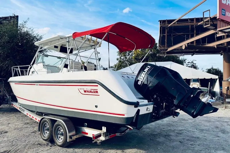 Slide: The Image of 2002 Boston Whaler boat with Suzuki outboard motor on a trailer, red canopy. - 2
