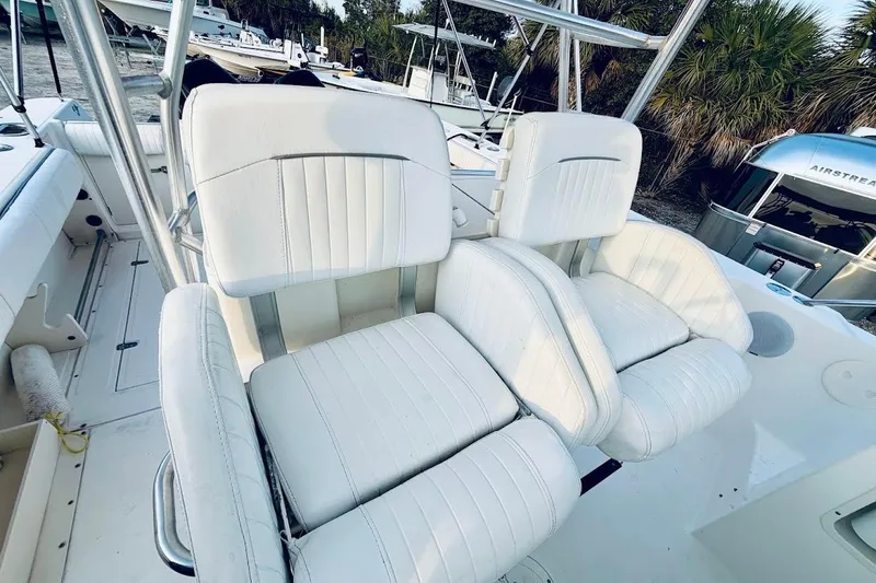 Slide: The Image of 2002 Boston Whaler boat with white cushioned seats, docked near palm trees. - 30