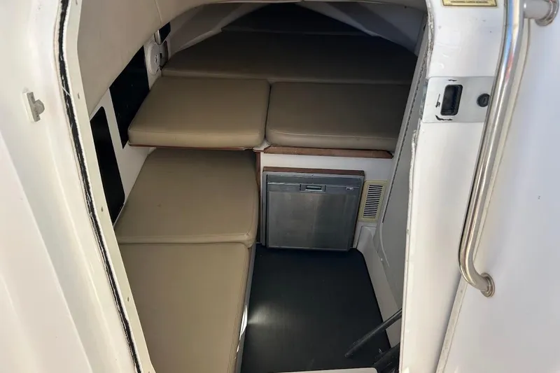 Slide: The Image of 2002 Boston Whaler boat cabin interior with cushioned seating and compact refrigerator. - 42