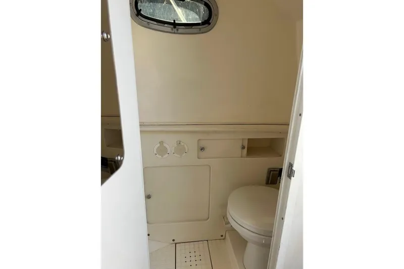 Slide: The Image of 2002 Boston Whaler boat interior bathroom with toilet and porthole window. - 44