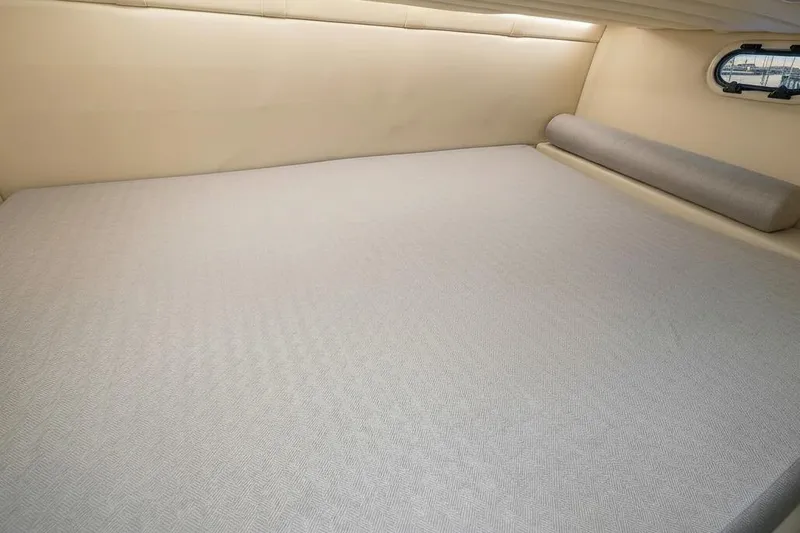Slide: The Image of 2020 Regal 26 XO cabin interior with beige bedding and a small window. - 12