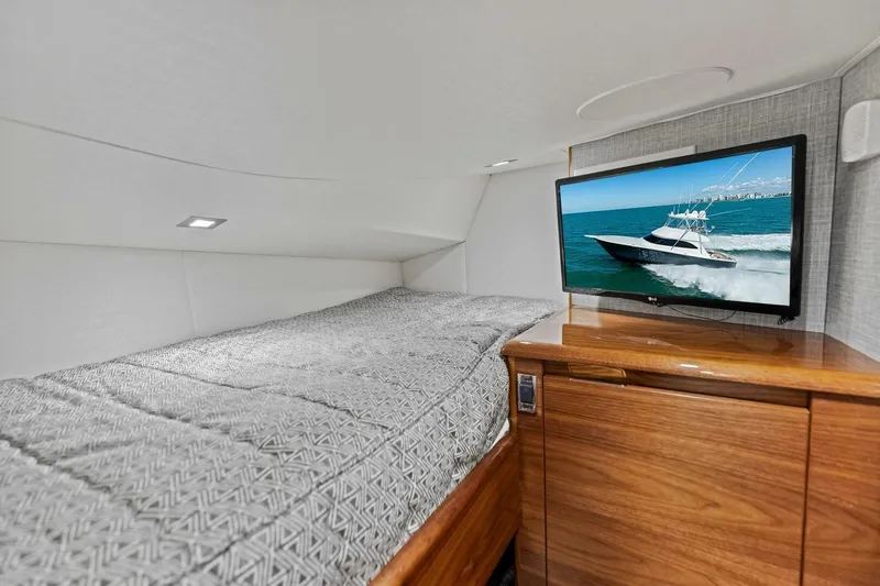 Slide: The Image of 2023 Vikiing convertible yacht interior with bed and TV displaying a boat scene. - 23