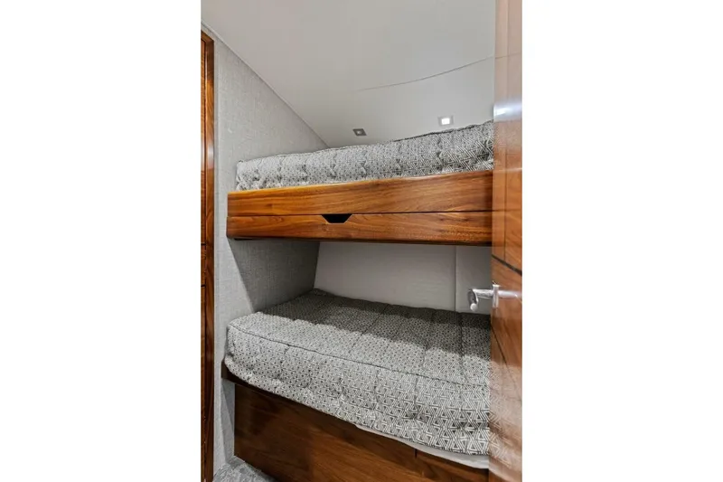 Slide: The Image of 2023 Vikiing convertible interior with wooden bunk beds and patterned cushions. - 24