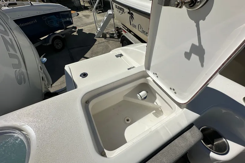 Slide: The Image of 2023 Sea Pro 239 Deep V CC boat with open storage compartment and visible Suzuki engine. - 17