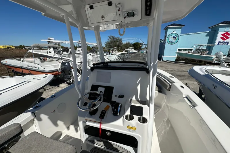 Slide: The Image of 2023 Sea Pro 239 Deep V CC boat interior with steering console and marina background. - 5