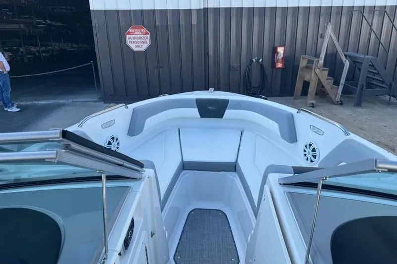 Slide: The Image of 2022 Chapparall 21 SSi boat interior with gray seating and speakers, docked near a building. - 5