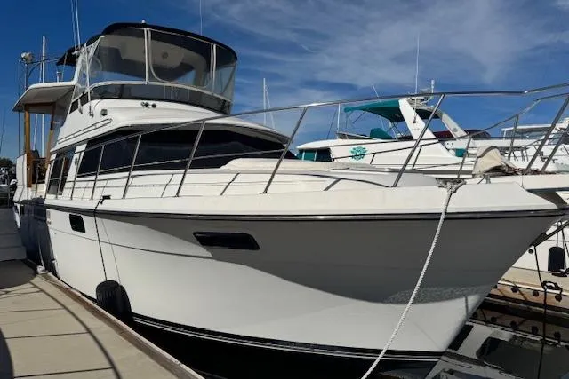 Slide: The Image of 1986 Carver 4207 Aft Cabin Motor Yacht docked at marina under blue sky. - 2