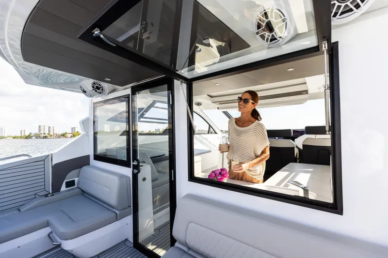 Slide: The Image of 2026 Cruisers Yachts 50 GLS interior with woman enjoying a drink, modern design. - 15