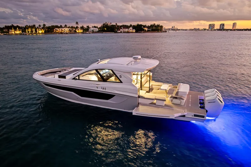 Slide: The Image of 2026 Cruisers Yachts 50 GLS on serene water at sunset, illuminated deck. - 7