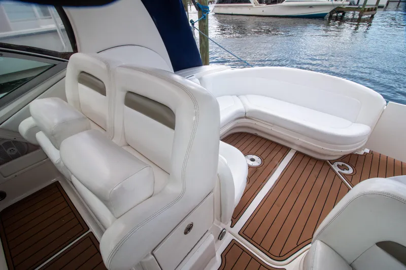 Slide: The Image of 2006 Sea Ray Sundancer 320 interior with white seating and teak flooring by the water. - 22
