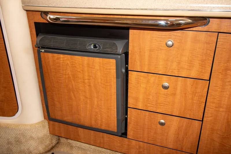 Slide: The Image of 2006 Sea Ray Sundancer 320 interior with wooden cabinetry and built-in mini fridge. - 45