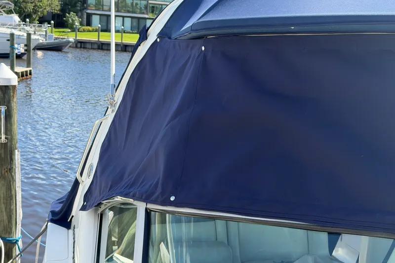 Slide: The Image of 2006 Sea Ray Sundancer 320 with blue canvas cover docked by the water. - 4