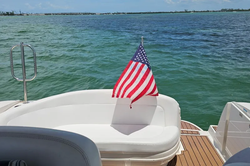 Slide: The Image of 2006 Sea Ray Sundancer 320 with American flag on deck, overlooking serene waters. - 9