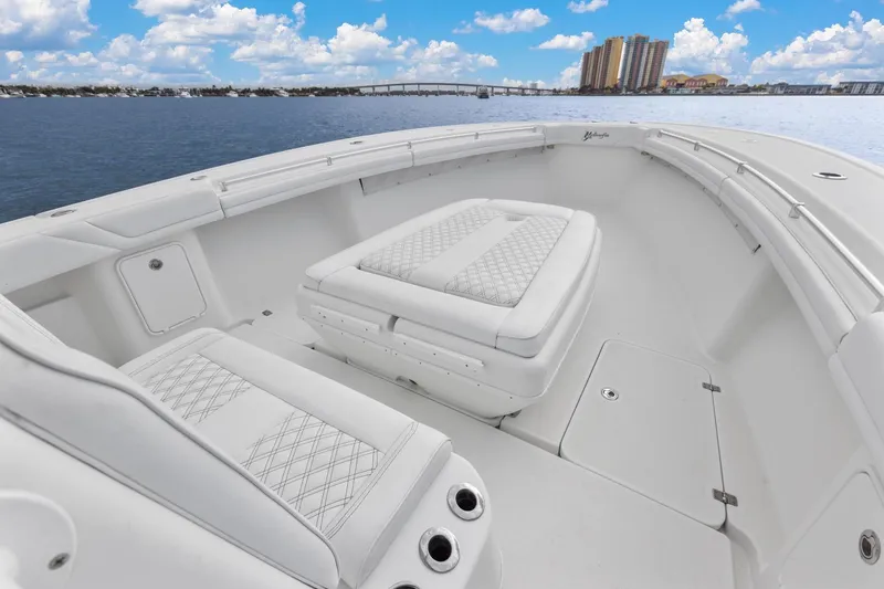 Slide: The Image of 2015 Yellowfin 39 Offshore boat interior with cushioned seating, ocean view, and city skyline. - 15