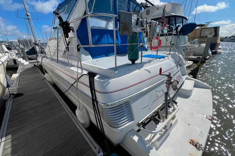 Slide: The Image of 1989 Bayliner 4285 Avanti deck with blue cover and life preserver, docked at marina. - 3