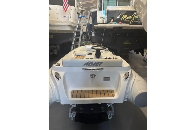 Slide: The Image of 2023 AB Inflatables ABJET 290 boat in a showroom, rear view with visible controls. - 10