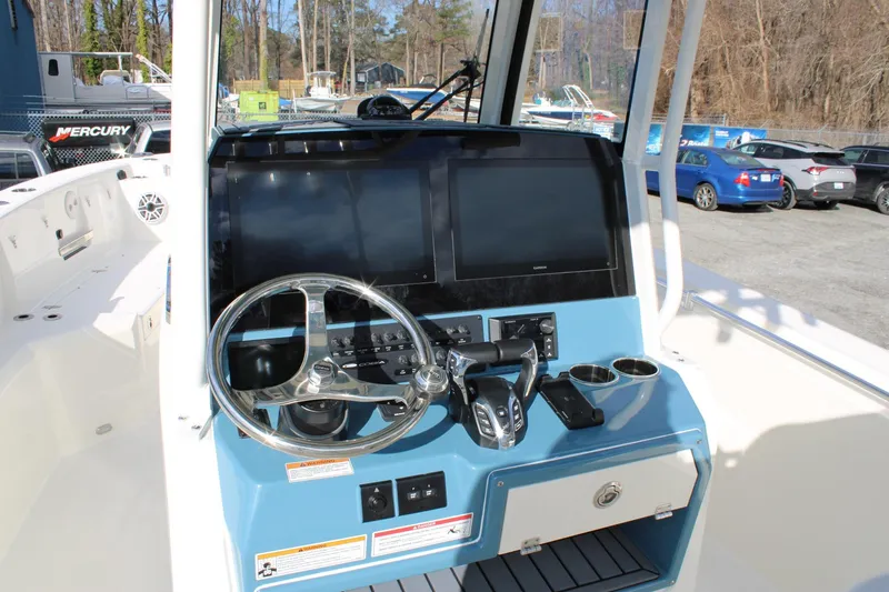 Slide: The Image of 2026 Cobia 285 Center Console boat dashboard with steering wheel and navigation screens. - 16