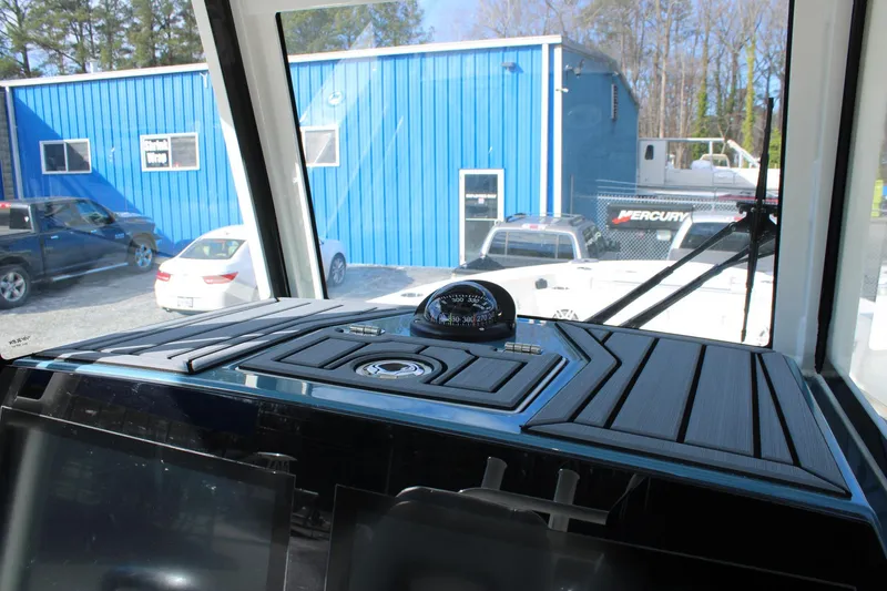 Slide: The Image of 2026 Cobia 285 Center Console dashboard with compass, parked near blue building. - 19