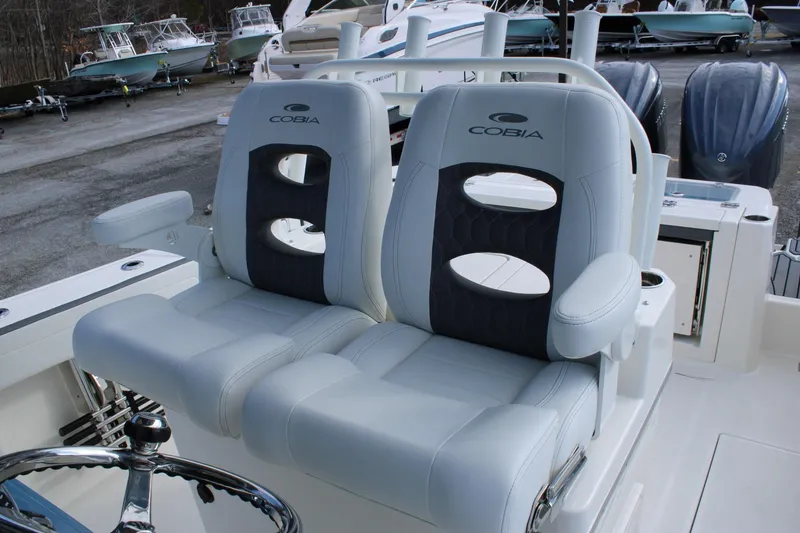 Slide: The Image of 2026 Cobia 285 Center Console boat seats with armrests, parked among other boats. - 25