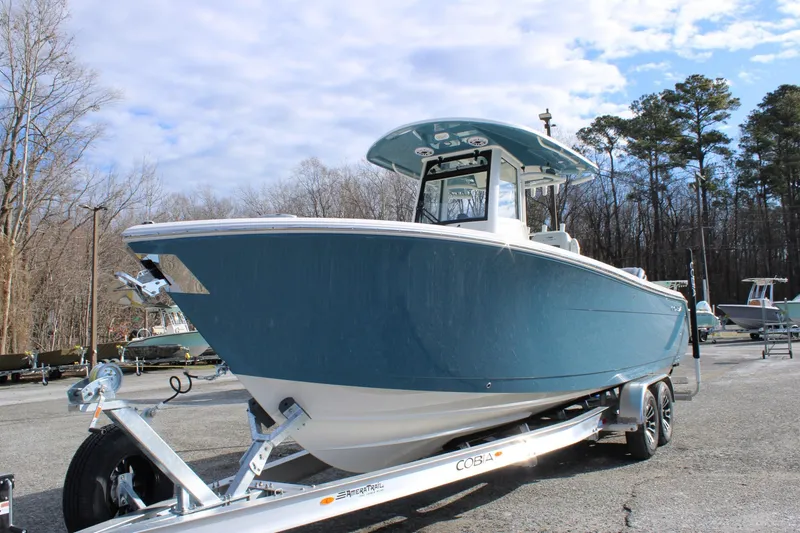 Slide: The Image of 2026 Cobia 285 Center Console boat on trailer, parked outdoors under a cloudy sky. - 8