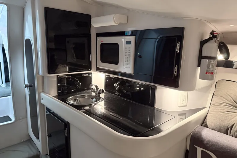 Slide: The Image of 2002 Donzi 38 ZX boat interior with kitchenette, featuring sink, microwave, and fire extinguisher. - 25