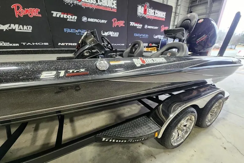 Slide: The Image of 2019 Triton 21 TrX boat on trailer in showroom with promotional banners. - 5