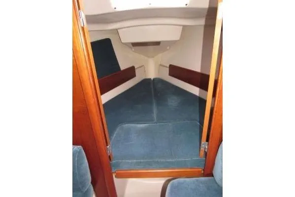 Slide: The Image of 1999 Beneteau Oceanis 321 cabin interior with blue cushions and wooden accents. - 10