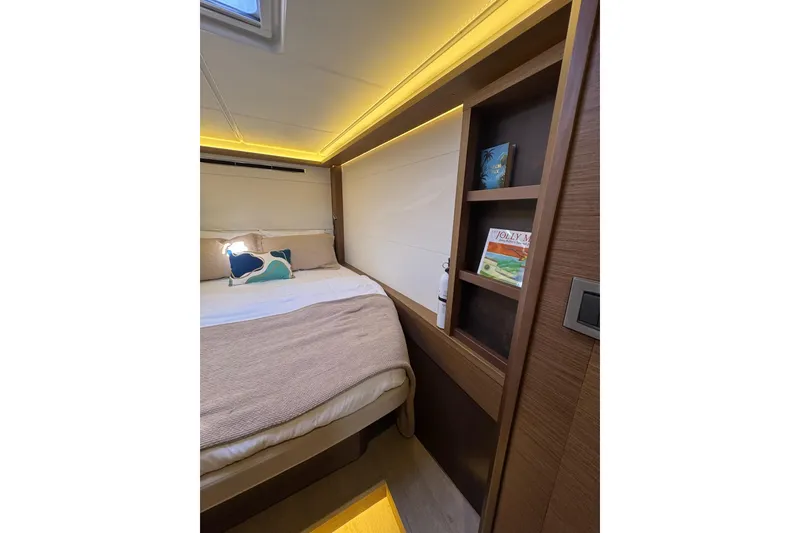 Slide: The Image of Cozy bedroom interior of 2020 Lagoon 46 yacht with ambient lighting and wooden shelves. - 33